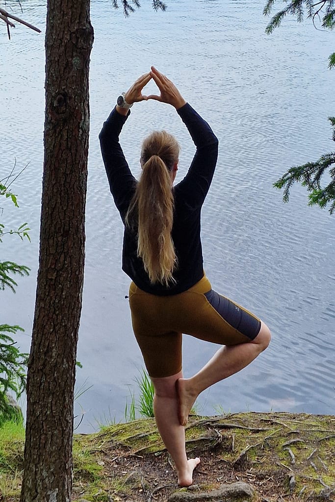 Kuvituskuva jossa nainen joogaa järveä vasten